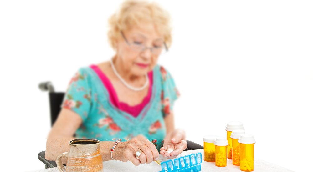 Senior woman in a wheelchair, counting out her pills for the week. 