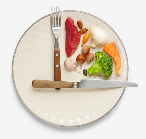 20:4 fasting diet concept. One-third plate with healthy food and the two-third plate is empty. Beef, salmon, egg, broccoli, tomato, nuts, carrots, mushrooms, cucumber, dates.