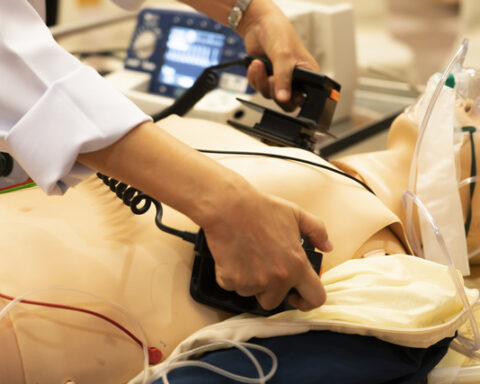 A white coat physician perform defibrillationon a doll during ACLS training program